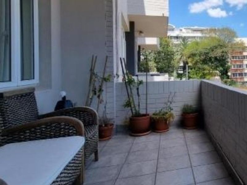 A covered balcony featuring tiled flooring and a brick balustrade, offering an outdoor space with views of the surrounding neighborhood.