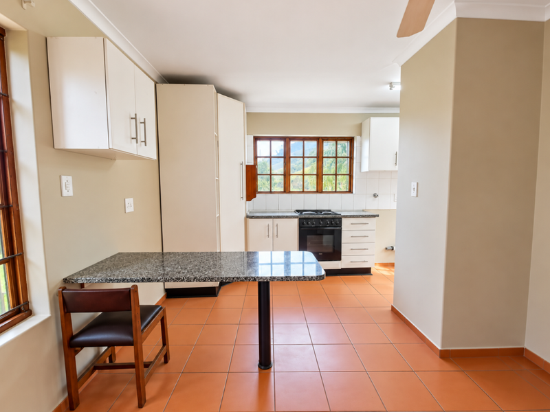 A functional kitchen featuring built-in cabinetry, granite countertops, a built-in oven and hob, and tiled flooring with a breakfast nook area.