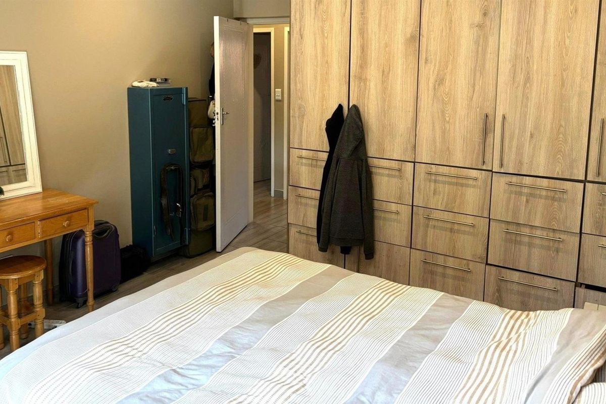 A bedroom featuring extensive built-in wooden cabinetry and laminate flooring, providing ample storage space and a neutral aesthetic.