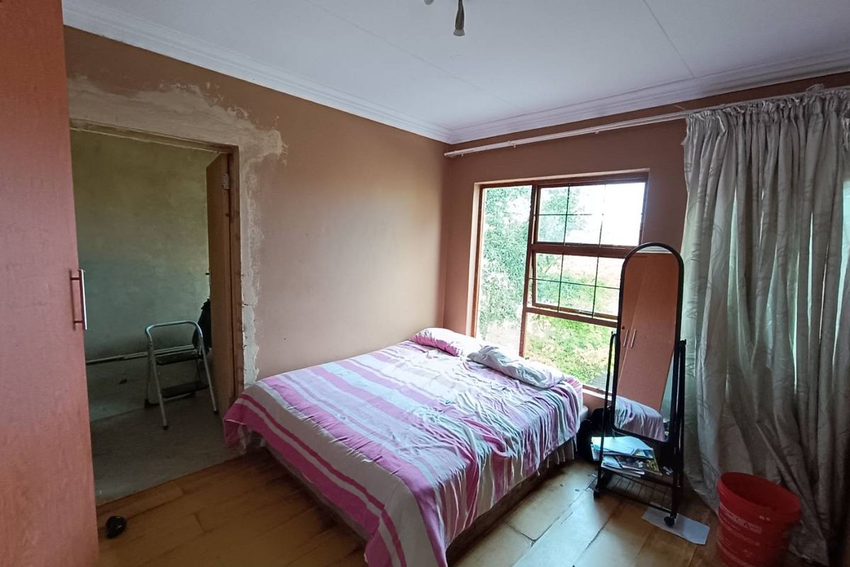A bedroom featuring wooden flooring and natural light, currently requiring cosmetic attention to the wall plaster around the doorway.