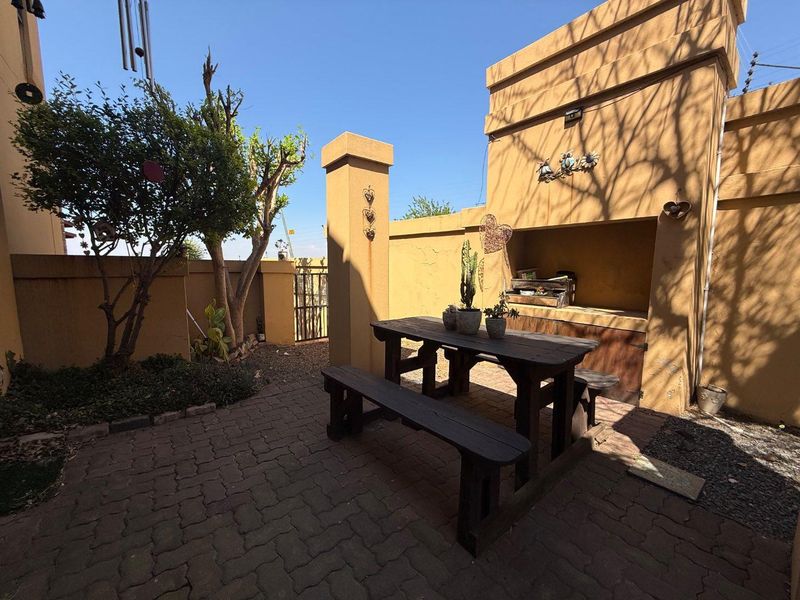 Outdoor patio area featuring a built-in braai, paved flooring, and enclosed by a boundary wall, providing a private space for outdoor entertainment.