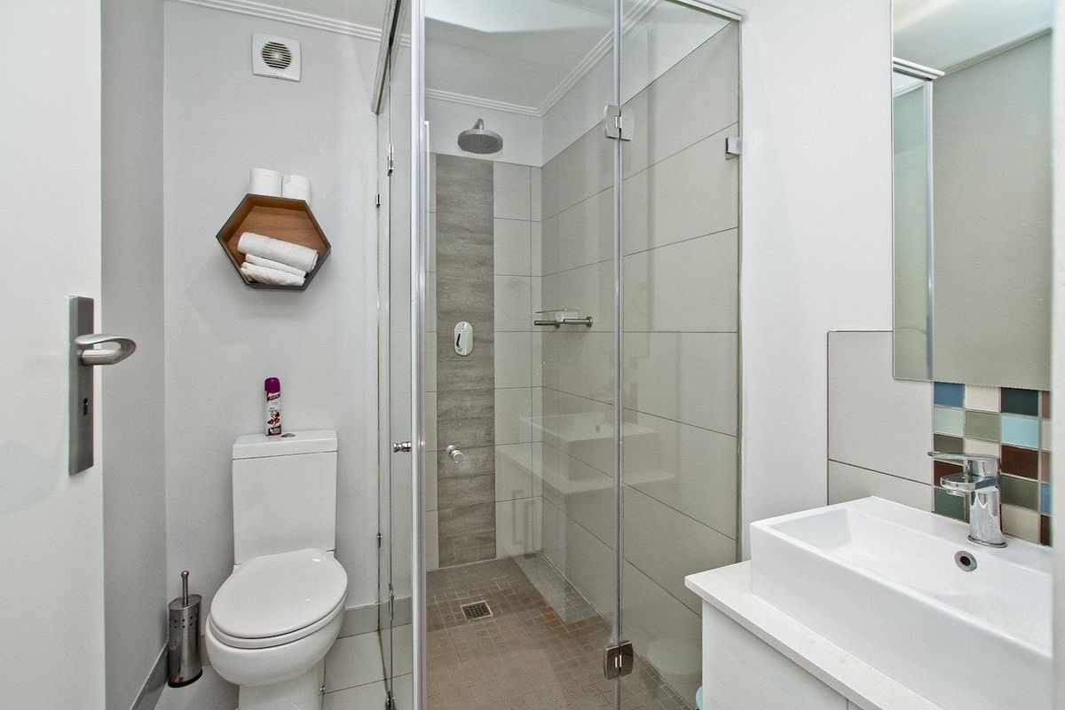 Modern bathroom featuring a glass-enclosed shower with tiled accents, a contemporary vanity basin, and a standard toilet.