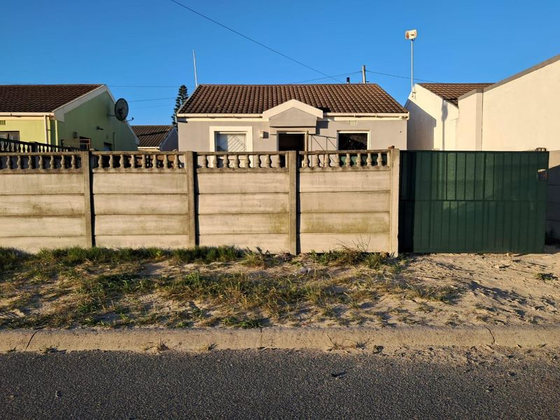 Front exterior view of a single-story house featuring a tiled roof, security bars, and a precast concrete boundary wall with a metal gate.