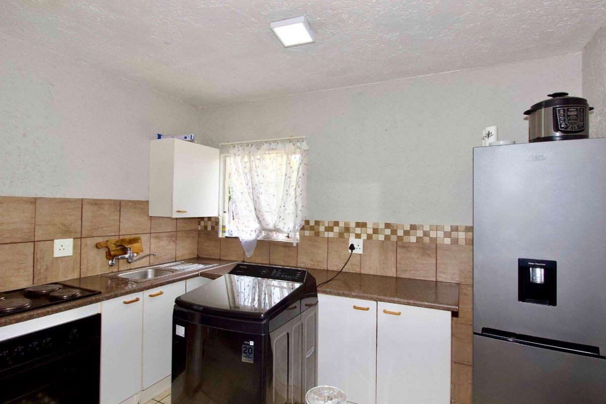 A functional kitchen featuring built-in cabinetry, a tiled backsplash, integrated oven and hob, and a stainless steel sink.