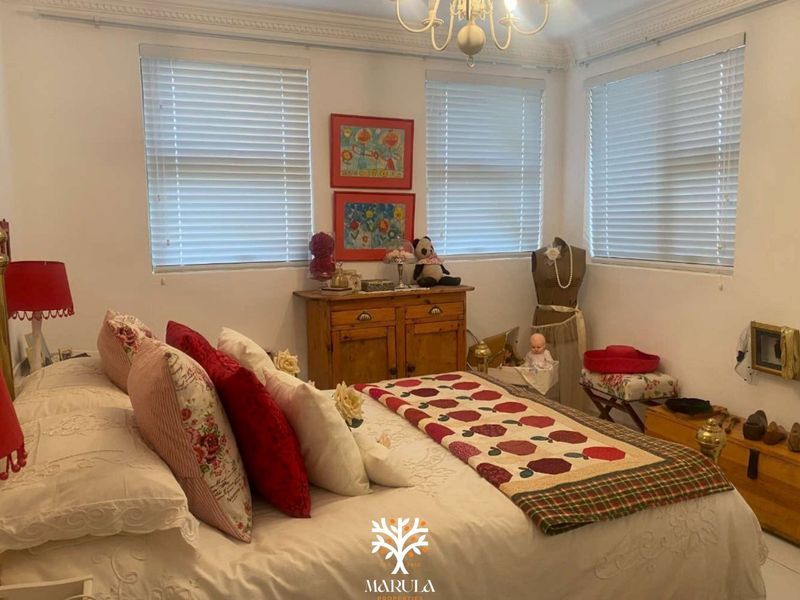 A cozy bedroom featuring crown molding, multiple windows with venetian blinds, and a central ceiling light fixture.