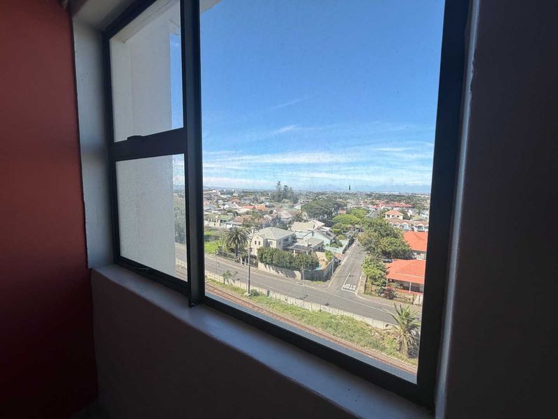 Elevated view overlooking the surrounding neighbourhood and streetscape, captured through a large aluminium-framed window.