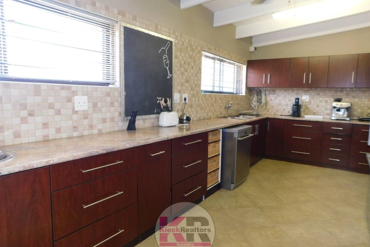 A functional kitchen featuring dark wood cabinetry, tiled splashbacks, laminate countertops, and a ceiling fan, offering ample storage and workspace.