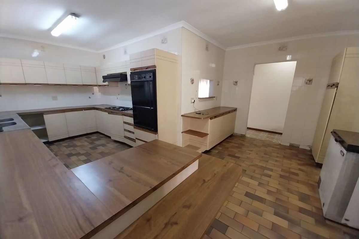 Spacious kitchen featuring built-in cabinetry, integrated oven and hob, and tiled surfaces, offering a functional layout ready for modernization.