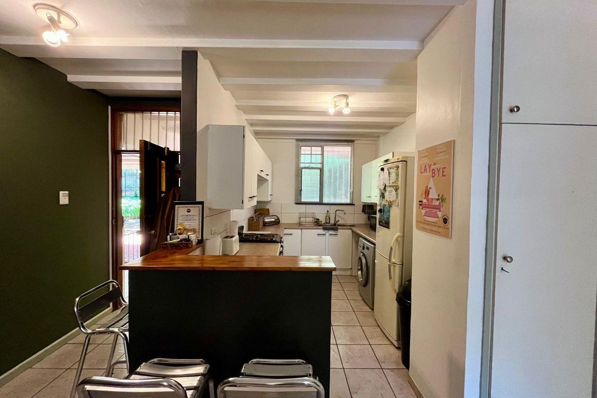 Functional kitchen featuring a breakfast bar, built-in cabinetry, tiled flooring, and exposed ceiling beams, with direct access to an exterior entrance.