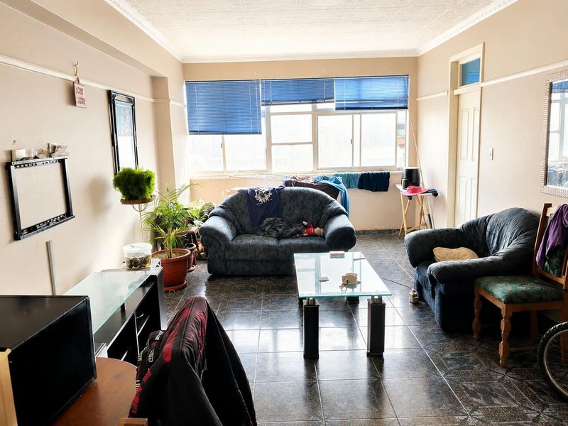 A living room featuring tiled flooring, decorative cornice, picture rails, and large windows with blue venetian blinds.