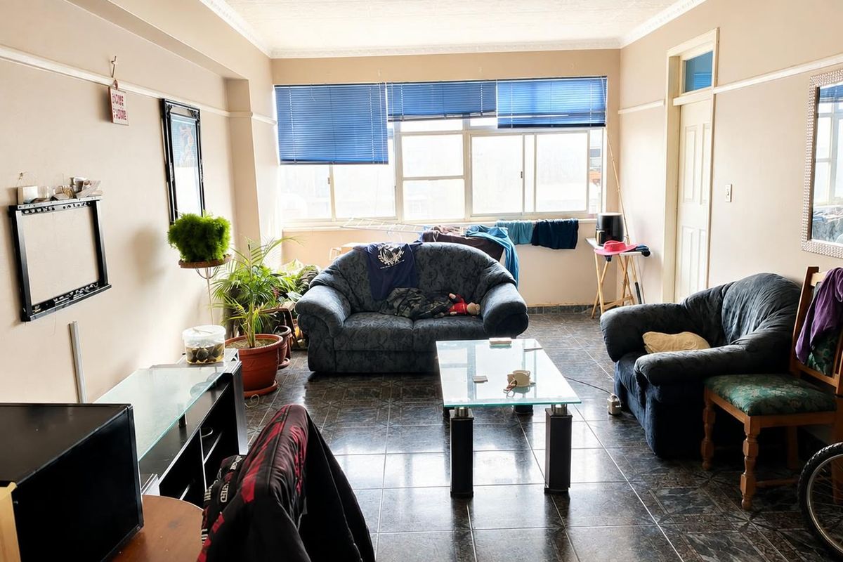 A living room featuring tiled flooring, decorative cornice, picture rails, and large windows with blue venetian blinds.