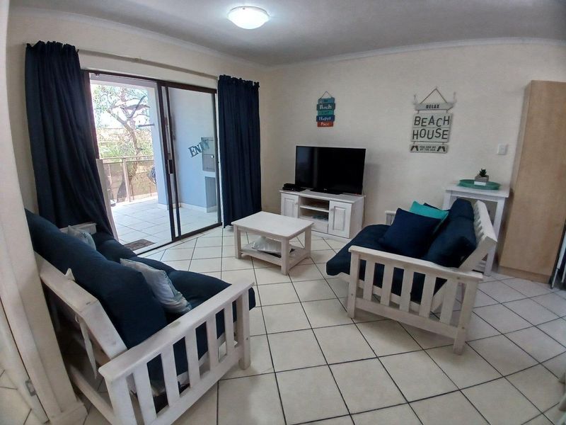 A living room featuring ceramic floor tiles and a sliding glass door providing access to an outdoor balcony area.