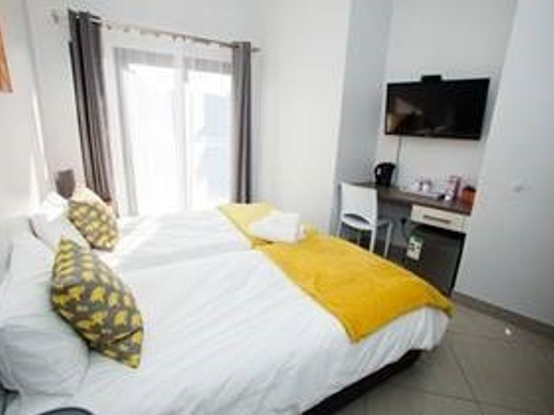 A compact bedroom featuring tiled flooring, a built-in desk area, and a sliding glass door providing natural light.