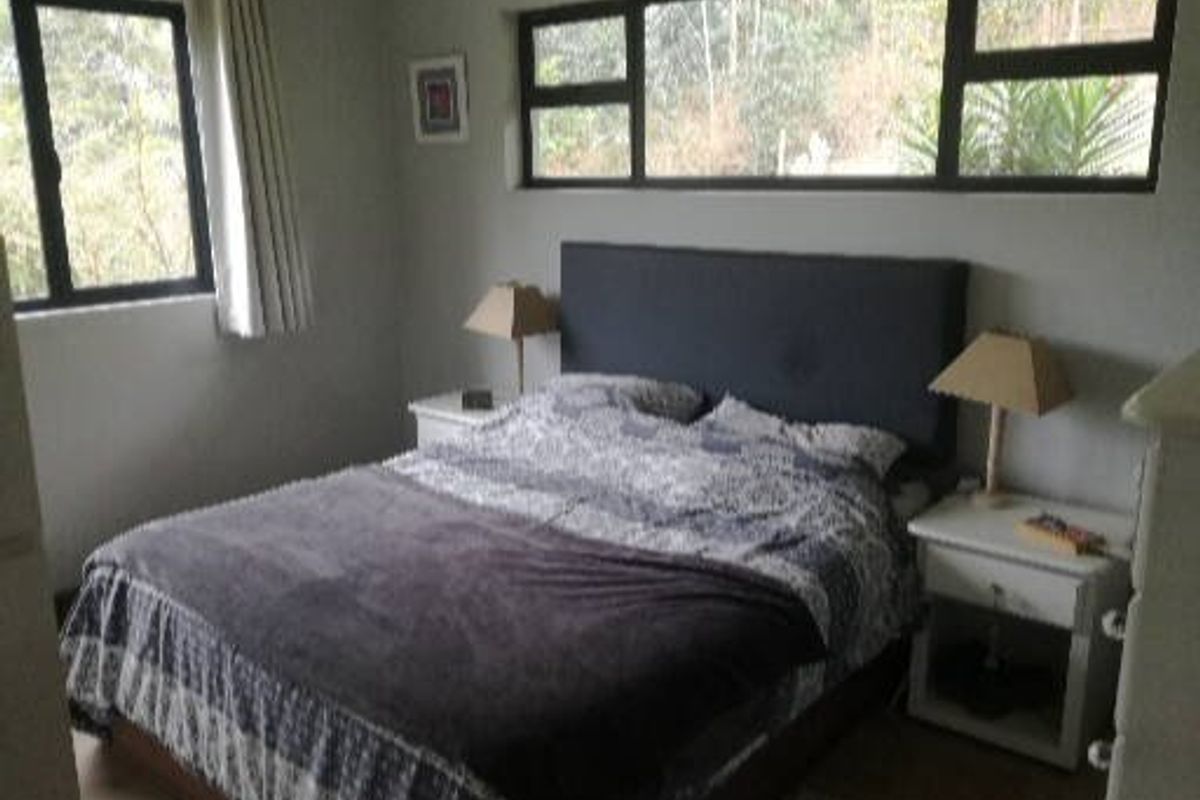 A bedroom featuring aluminium window frames and natural light, providing a comfortable space for rest.