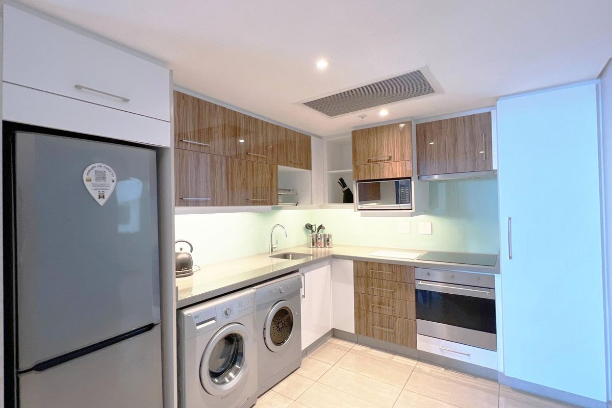 Modern kitchen featuring wood-grain and white cabinetry, stone countertops, integrated appliances, and recessed lighting in a clean, functional layout.