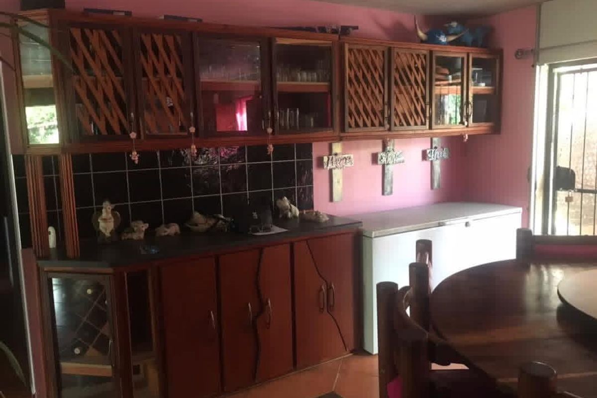 A dated kitchen area featuring wooden cabinetry, black tiled backsplash, and laminate countertops, offering potential for a modern renovation.