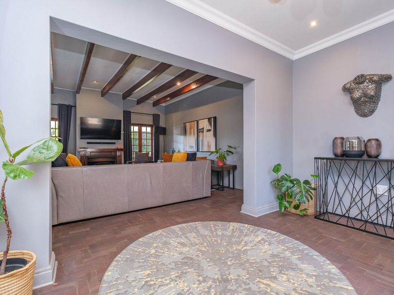 Open plan living area featuring elegant herringbone parquet flooring, exposed timber ceiling beams, and a cozy fireplace, creating a warm and inviting atmosphere.