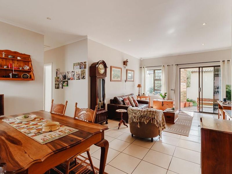 Spacious open-plan living and dining area featuring tiled flooring, recessed lighting, and large sliding glass doors providing direct access to the rear patio.