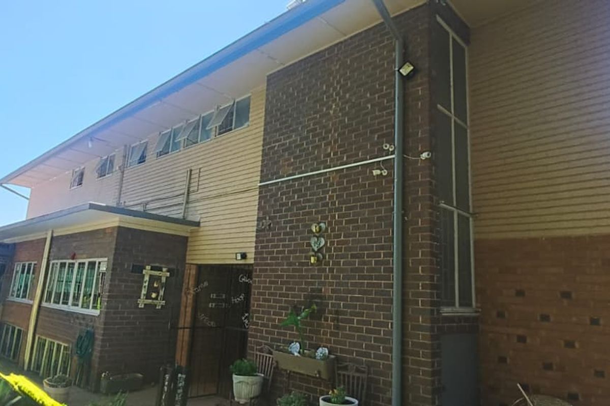 Rear elevation of a two-story house featuring a combination of brick and weatherboard cladding with multiple casement windows.
