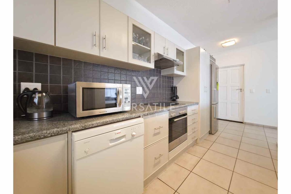 A functional kitchen featuring granite countertops, tiled backsplash, built-in oven, extractor fan, and ample cabinetry for storage.