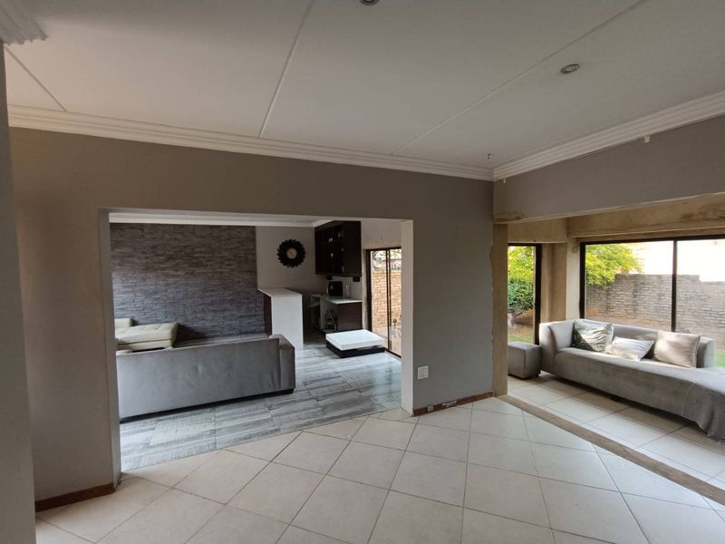 Open-plan living area featuring tiled floors, recessed lighting, and sliding glass doors leading to the exterior, with some areas requiring finishing touches.