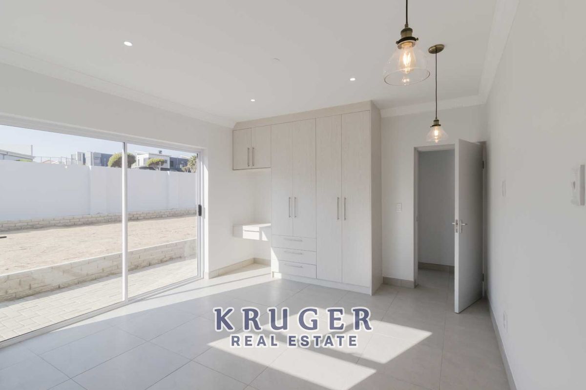 Bright bedroom featuring built-in cabinetry, tiled flooring, recessed lighting, and large sliding glass doors providing direct access to the rear yard.