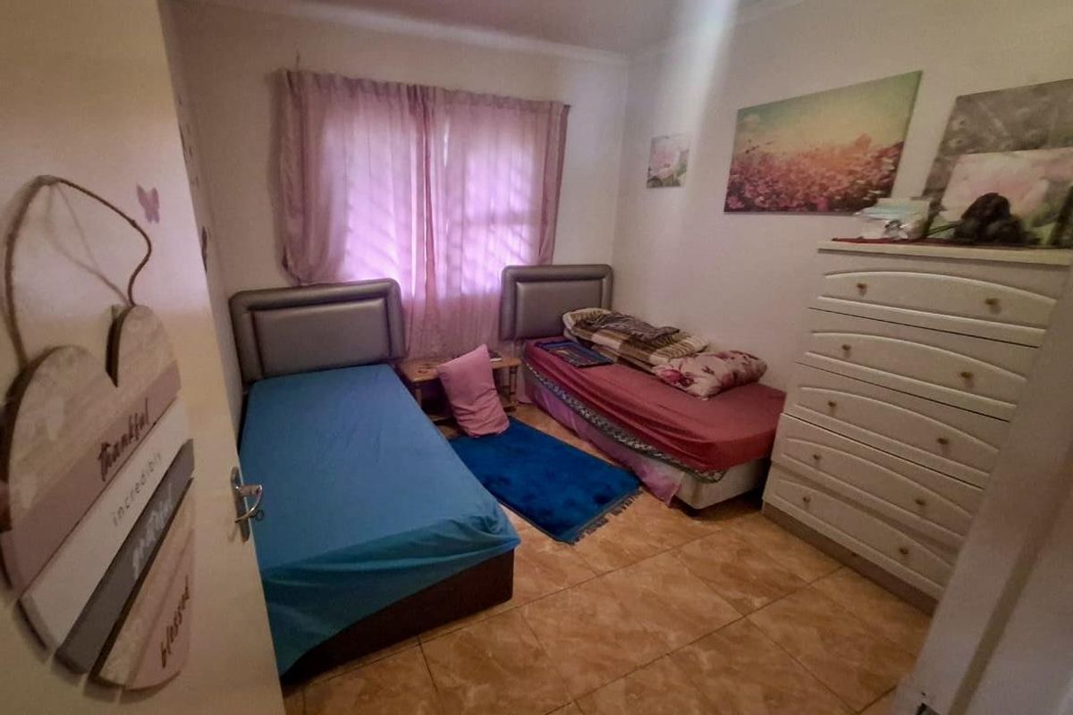 A functional bedroom featuring tiled flooring and a window with curtains, providing a comfortable space for sleeping.