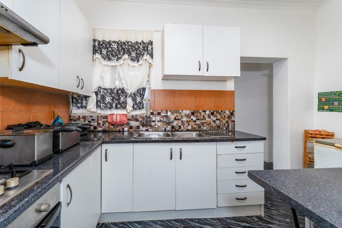 A functional kitchen featuring white cabinetry, dark laminate countertops, a double-basin sink, and a built-in oven with extractor fan.