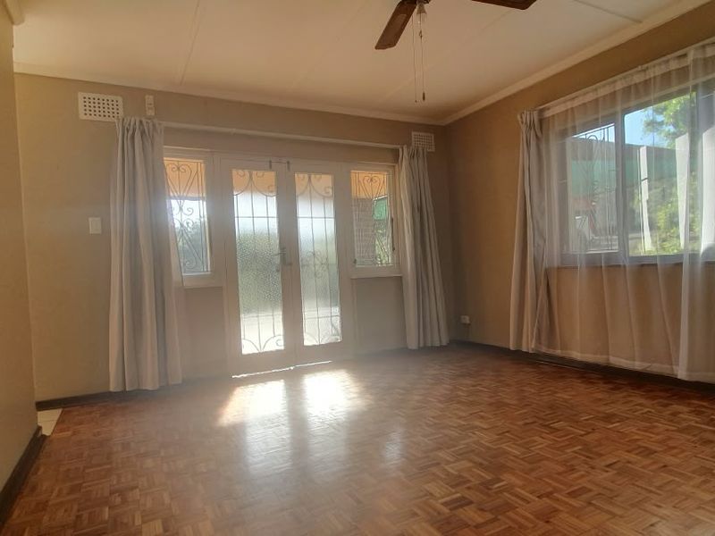 Spacious living room featuring classic parquet flooring, a ceiling fan, and direct access to the exterior through secure french doors.