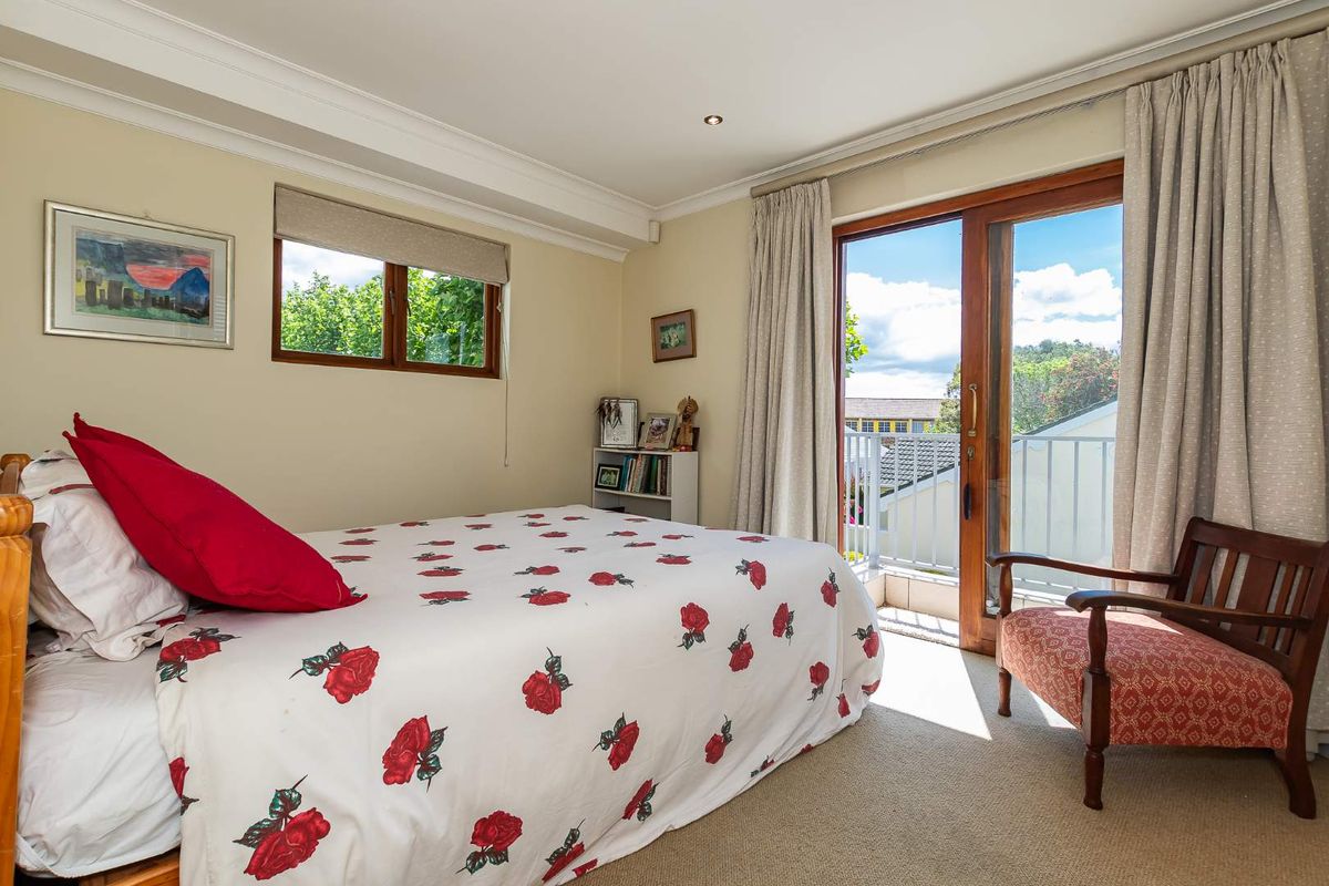 A well-lit bedroom featuring neutral walls, carpeted flooring, and sliding glass doors that open onto a private balcony.