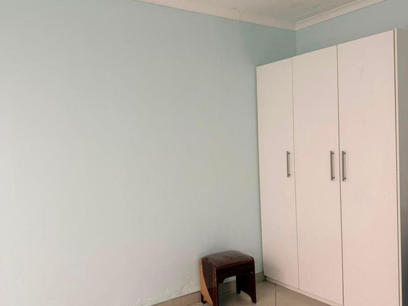 A bedroom featuring tiled flooring, a built-in wardrobe, and coved ceiling details.