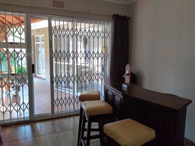 Living area featuring a built-in bar and sliding glass doors with security gates, providing direct access to the outdoor patio space.