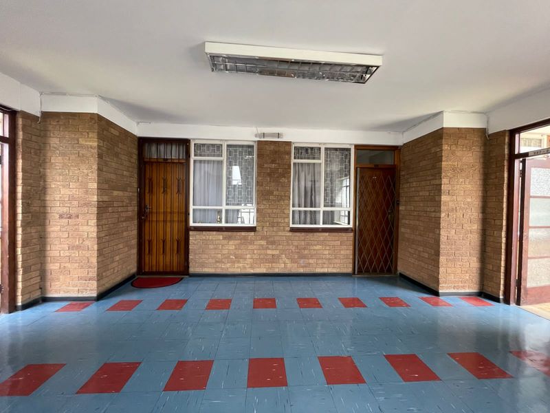 An empty entrance area featuring exposed brick walls, security gates, and patterned tiled flooring, providing a functional and secure access point to the apartment.