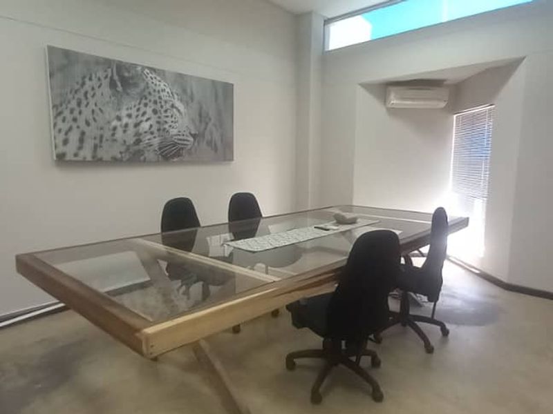 A functional office space featuring polished concrete floors, an integrated air conditioning unit, and a high-level clerestory window providing natural light.