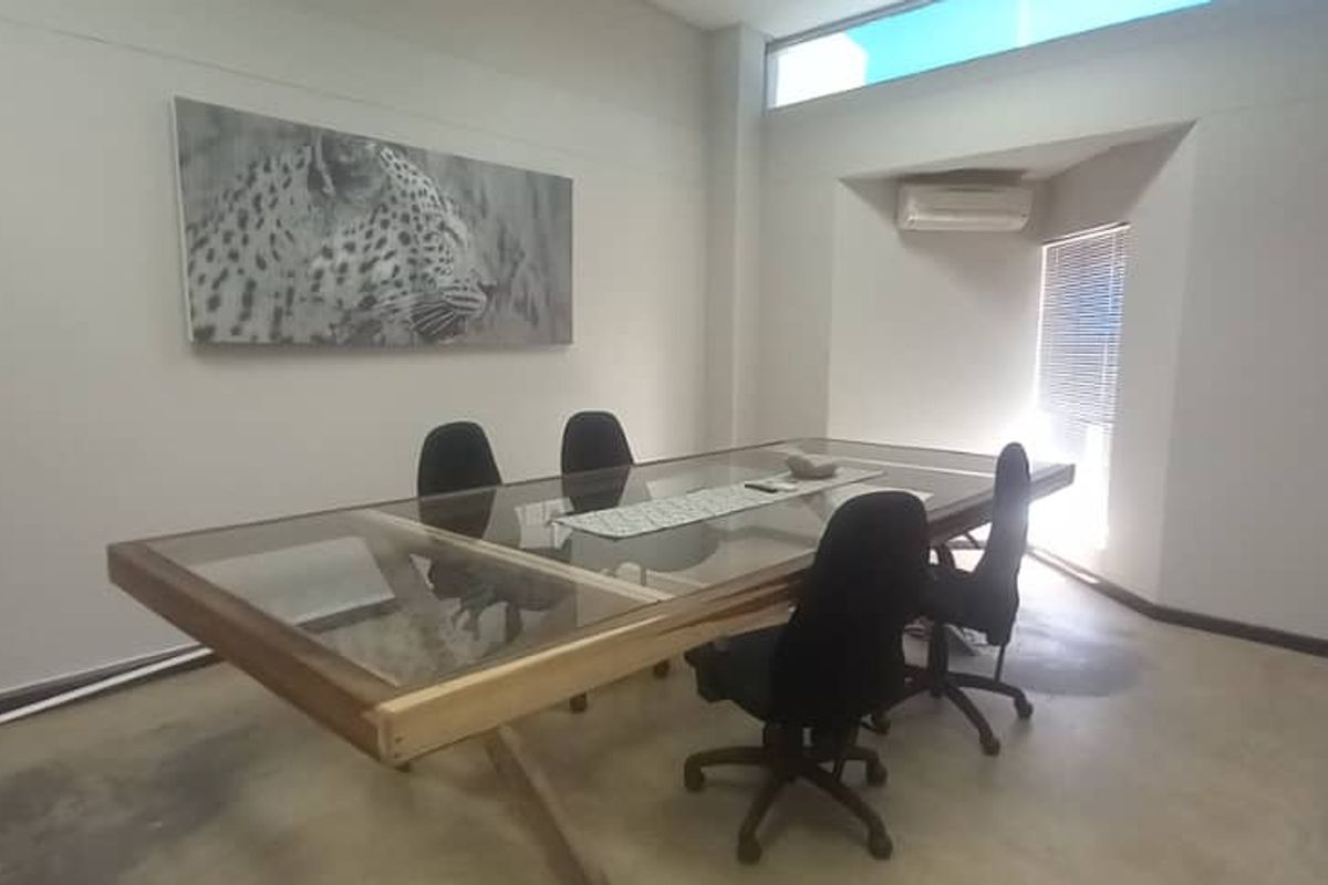 A functional office space featuring polished concrete floors, an integrated air conditioning unit, and a high-level clerestory window providing natural light.