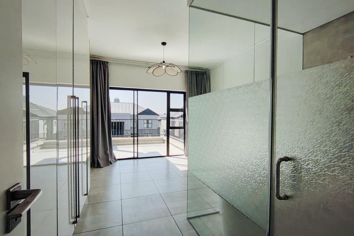 Modern bedroom featuring large built-in cupboards, tiled flooring, and sliding glass doors leading to a private balcony with a glass-enclosed shower area.