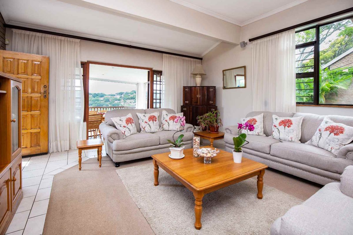 Spacious living room featuring tiled and carpeted flooring, large windows, and sliding doors leading to an outdoor patio area.