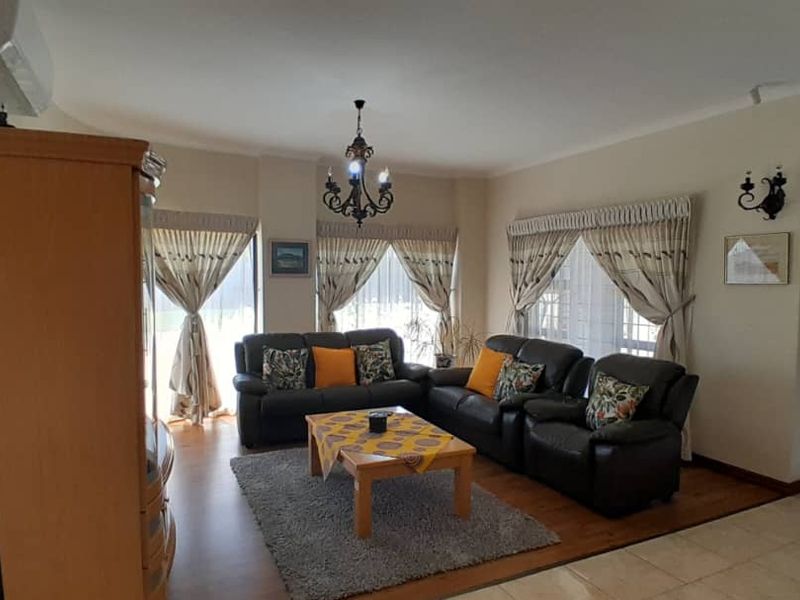Spacious living room featuring a combination of hardwood and tiled flooring, split-system air conditioning, and a classic timber entrance door.