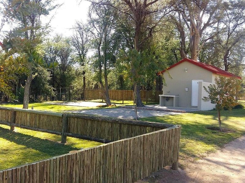 A well-maintained outdoor area featuring a concrete utility sink, paved slab, and rustic wooden fencing set within a landscaped garden environment.