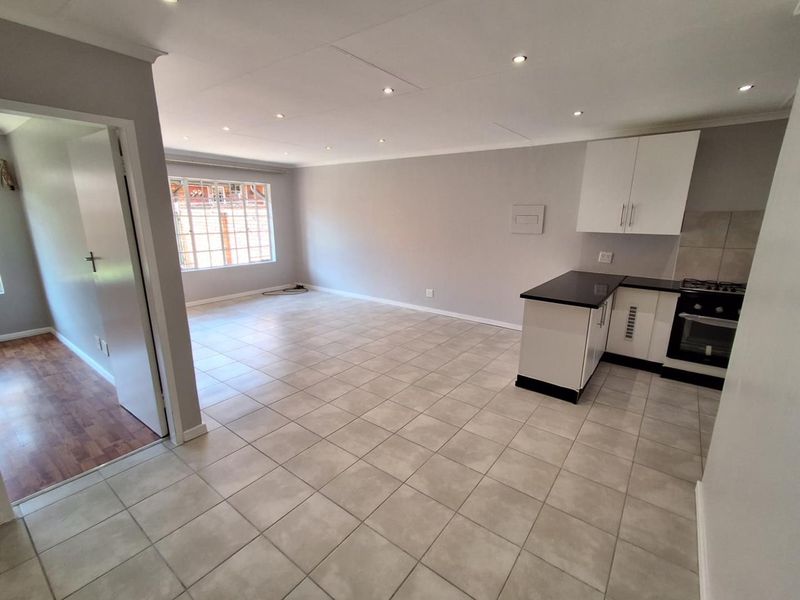 Spacious open-plan living area featuring tiled floors, recessed lighting, and a modern kitchen with built-in cabinetry, granite countertops, and integrated oven and hob.