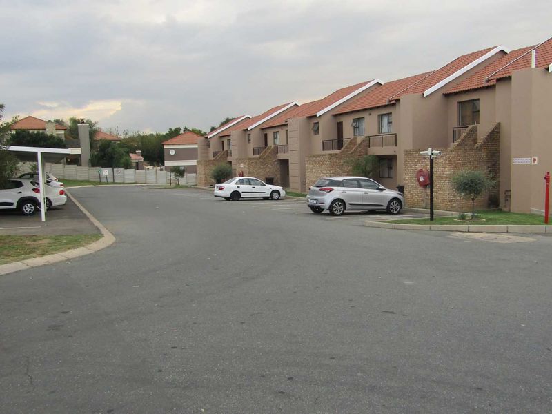 Exterior view of a residential apartment complex featuring brick facades, tiled roofs, balconies, and dedicated parking areas.