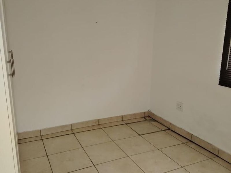 An empty bedroom featuring neutral tiled flooring and plain walls, providing a blank canvas for potential interior design and furnishing.