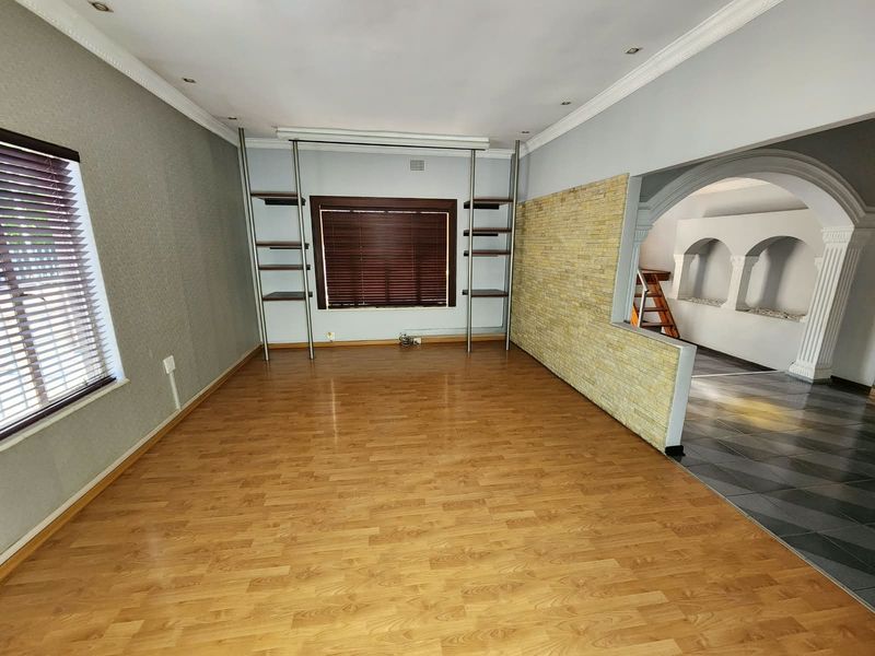 Spacious living area featuring laminate flooring, a stone feature wall, and elegant archways leading to an adjacent space.