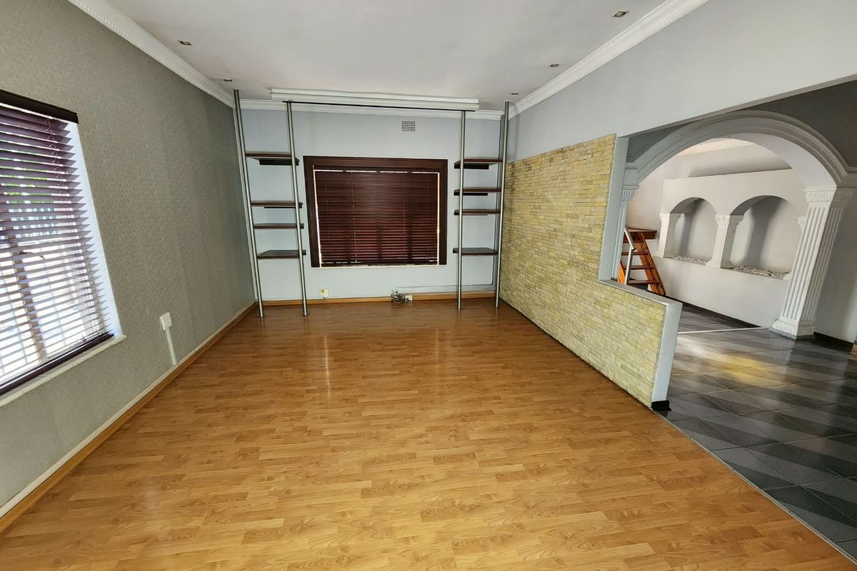 Spacious living area featuring laminate flooring, a stone feature wall, and elegant archways leading to an adjacent space.