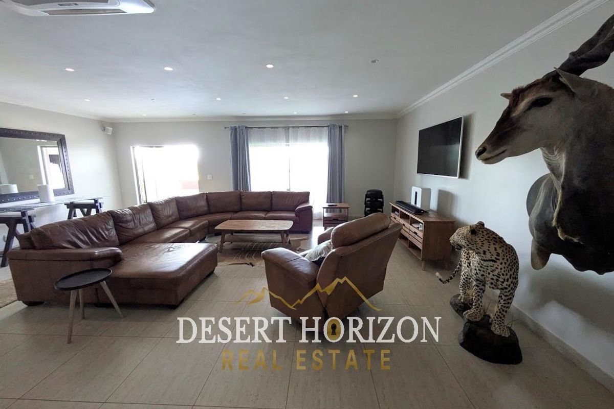 Spacious living room featuring large format floor tiles, recessed ceiling lighting, and integrated air conditioning unit.