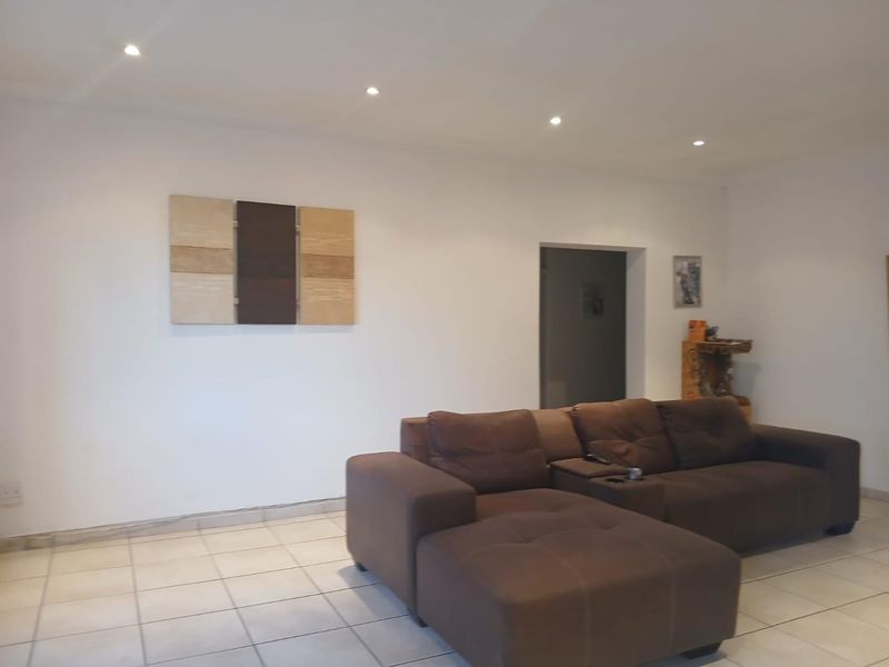 A living room featuring neutral ceramic floor tiles and recessed downlighting, providing a clean and functional space.
