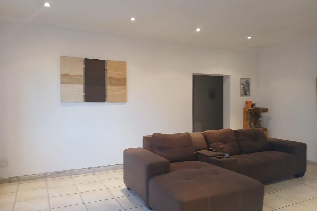 A living room featuring neutral ceramic floor tiles and recessed downlighting, providing a clean and functional space.