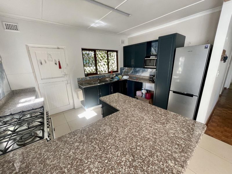 Functional kitchen featuring dark cabinetry, granite countertops, a gas hob, and a double basin sink with tiled flooring.