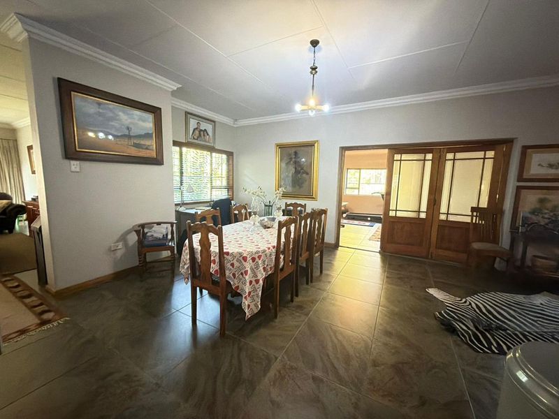 Spacious dining room featuring large floor tiles, decorative ceiling cornicing, and wooden sliding doors leading to an adjacent living area.