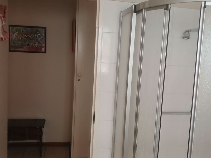 A functional bathroom featuring a corner shower enclosure with tiled walls and a standard shower head.